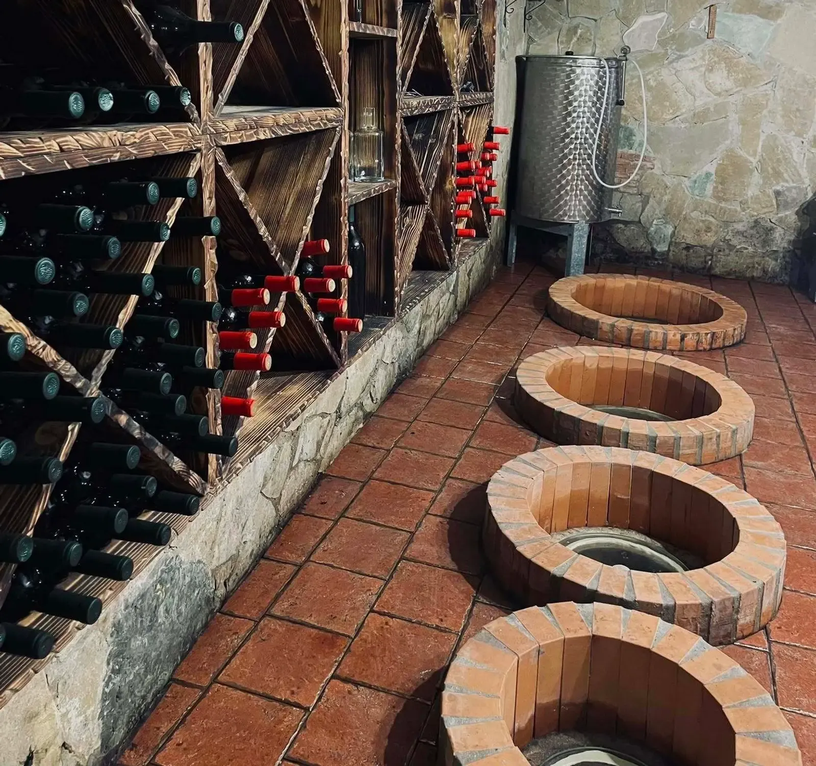 Cantina georgiana con coperchi di qvevri interrati e rastrelliere di bottiglie