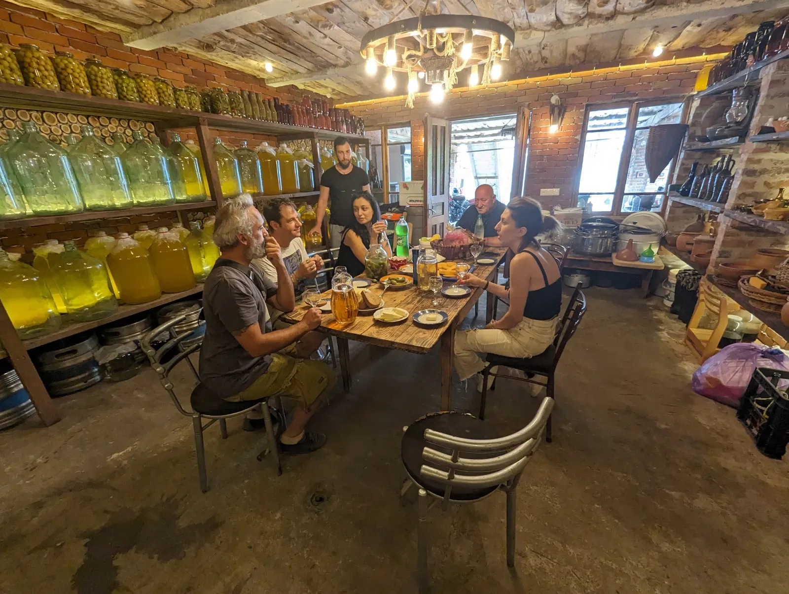 Degustazione di vini naturali attorno a un tavolo, fra le damigiane di una cantina georgiana